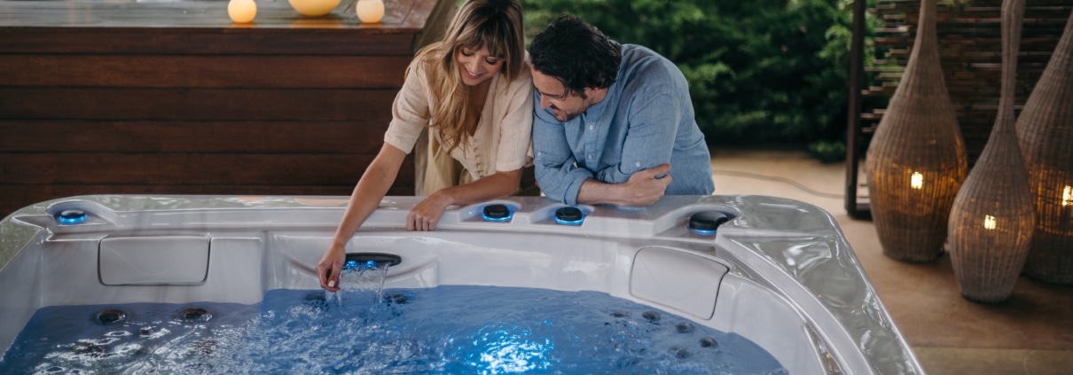 Spa con dos personas juntas en le exterior tocando el agua con cromoterapia azul
